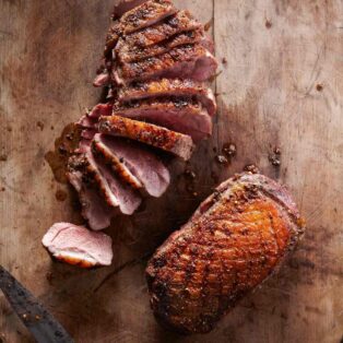 Sliced duck breast and whole duck breast on cutting board